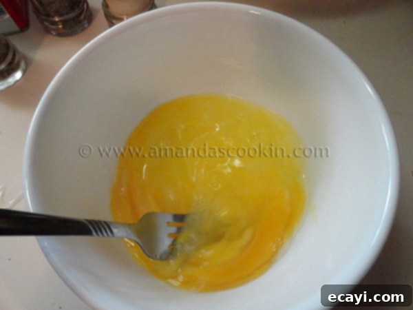 homemade-chicken-nuggets-step-5 A white bowl filled with three thoroughly whisked eggs, appearing frothy and light, ready for coating.