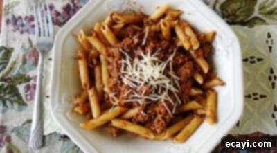 Over 40 Delicious Ground Beef Dinner Recipes 4 An overhead photo of perfectly cooked penne Bolognese, garnished with freshly grated parmesan cheese on top.
