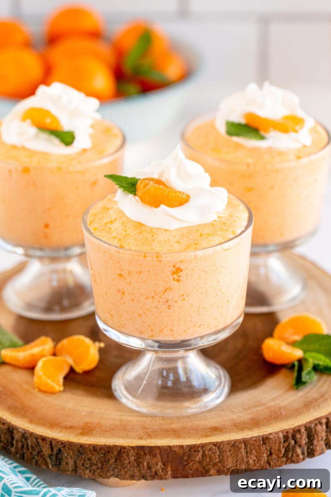 Sunshine Mandarin Whipped Mousse 2 Three individual dessert cups filled with light, fluffy whipped mandarin orange mousse, ready to serve.