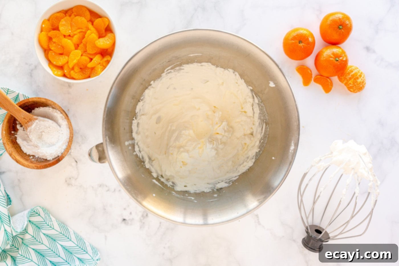 Sunshine Mandarin Whipped Mousse 7 Powdered sugar being added to heavy whipping cream in a mixing bowl before whipping.