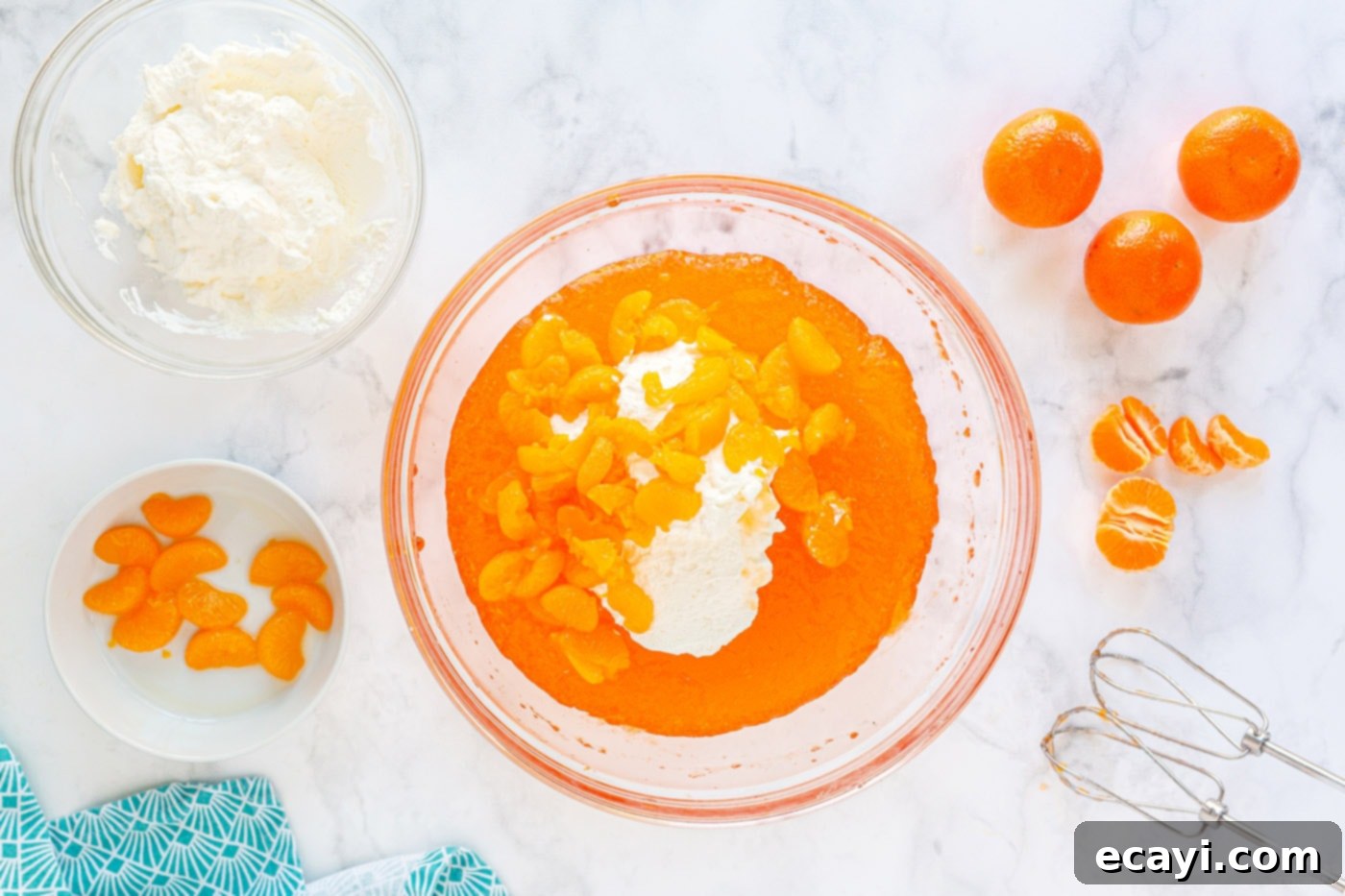 Sunshine Mandarin Whipped Mousse 8 All mousse ingredients – whipped cream, beaten jello, and mandarin oranges – being mixed in a large bowl.