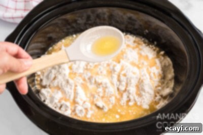 Cozy Apple Cobbler 9 Melted butter being spooned over the dry cake mix layer in the crockpot.