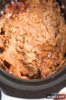 Cozy Apple Cobbler 10 Cooked apple dump cake in the crockpot, showing a golden brown topping and bubbly apple filling.