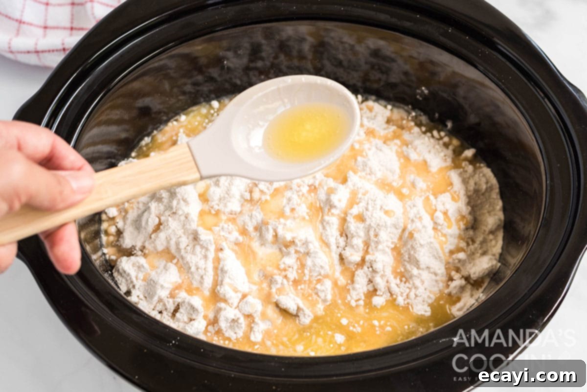 Cozy Apple Cobbler 6 Melted butter being spooned over the dry cake mix layer in the crockpot.