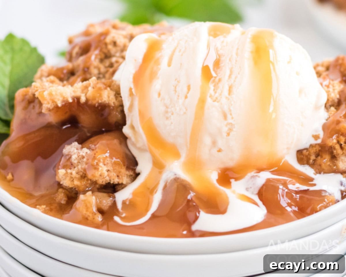 Make crockpot apple cobbler in your slow cooker. This easy crockpot dessert is quick & simple and great any time of year. A close-up of crockpot apple cobbler with melting vanilla ice cream and a drizzle of caramel sauce.