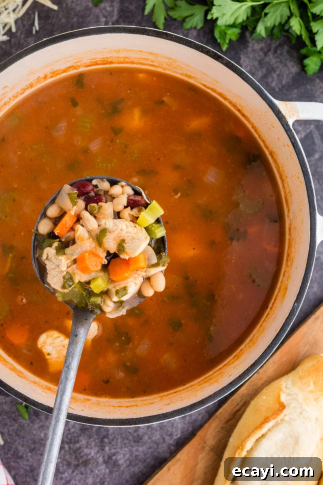 Homestyle Chicken Bean Warmth 2 Ladle full of rich, red chicken bean soup in a white bowl, ready to be served, highlighting the chunks of chicken and beans.