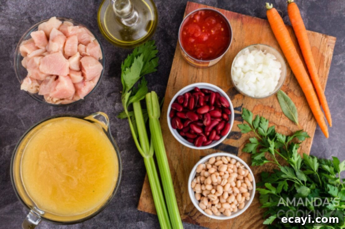 Homestyle Chicken Bean Warmth 4 A collection of fresh and canned ingredients laid out on a wooden surface, including chopped carrots, celery, onions, chicken breasts, canned beans, canned tomatoes, and fresh parsley, all ready for the chicken bean soup.