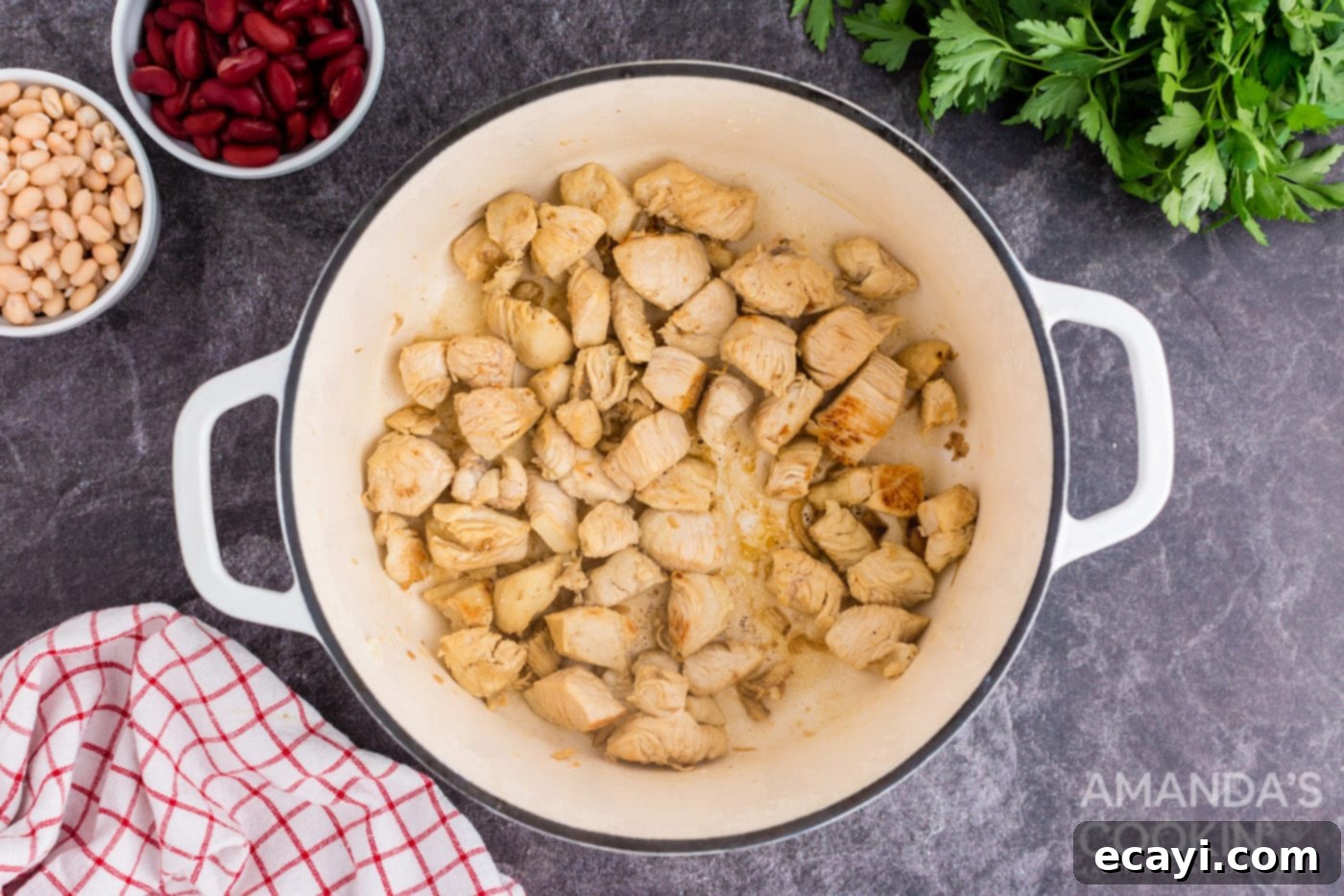 Homestyle Chicken Bean Warmth 5 Cubed chicken breasts being sautéed in a Dutch oven with olive oil until golden brown, before being removed from the pot.