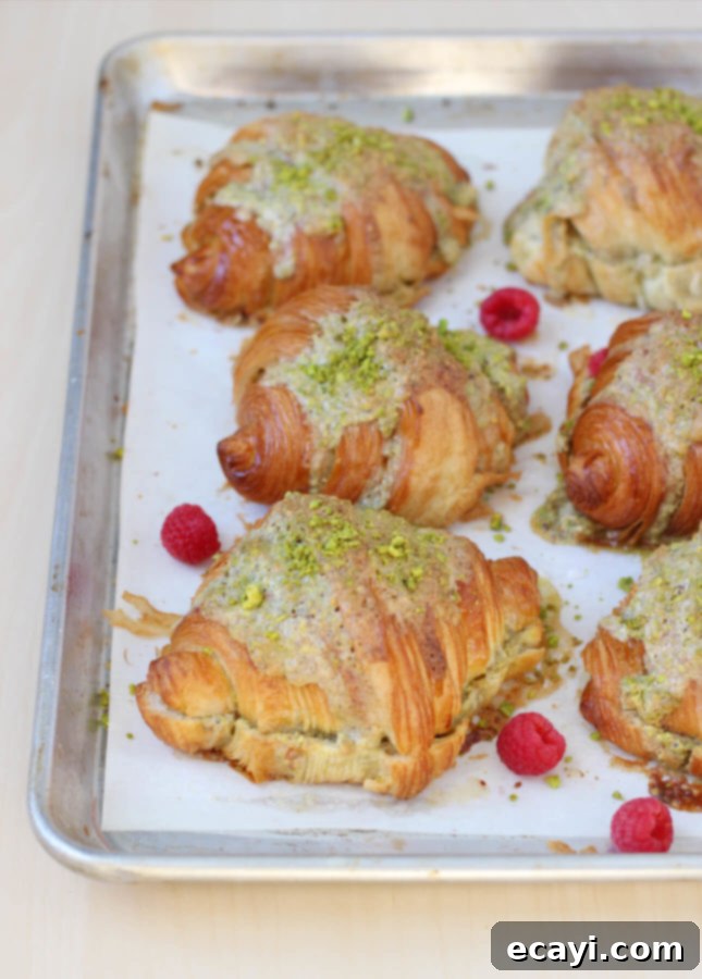 Effortless Pistachio Croissant Indulgence 5 Closeup of a freshly baked Pistachio Croissant, garnished with berries and powdered sugar.