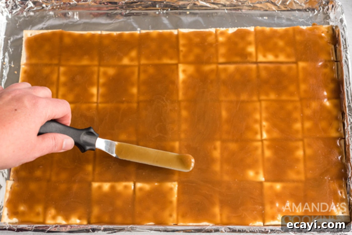 Salty Sweet Toffee Crunch 9 spatula spreading caramel over saltine crackers