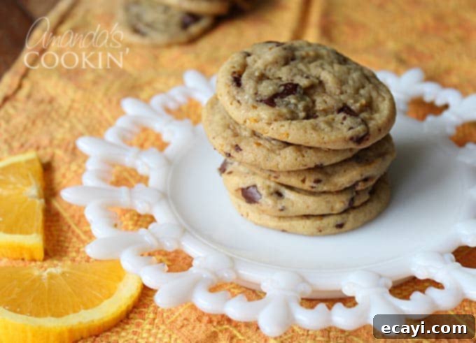 Citrus-Kissed Chocolate Chip Treats 5 A lovely stack of baked orange chocolate chip cookies resting on a pristine white plate, showcasing their golden-brown edges and inviting appearance.