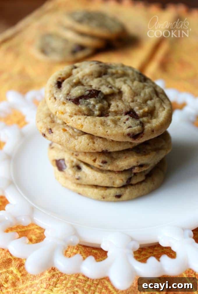 Citrus-Kissed Chocolate Chip Treats 7 A stack of orange chocolate chip cookies on a white plate, ready for a taste.