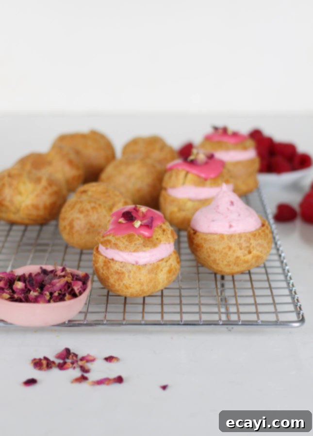 Raspberry Rose Cloud Puffs 6 A close-up of a filled Rose Raspberry Fool Cream Puff on a cooling rack.