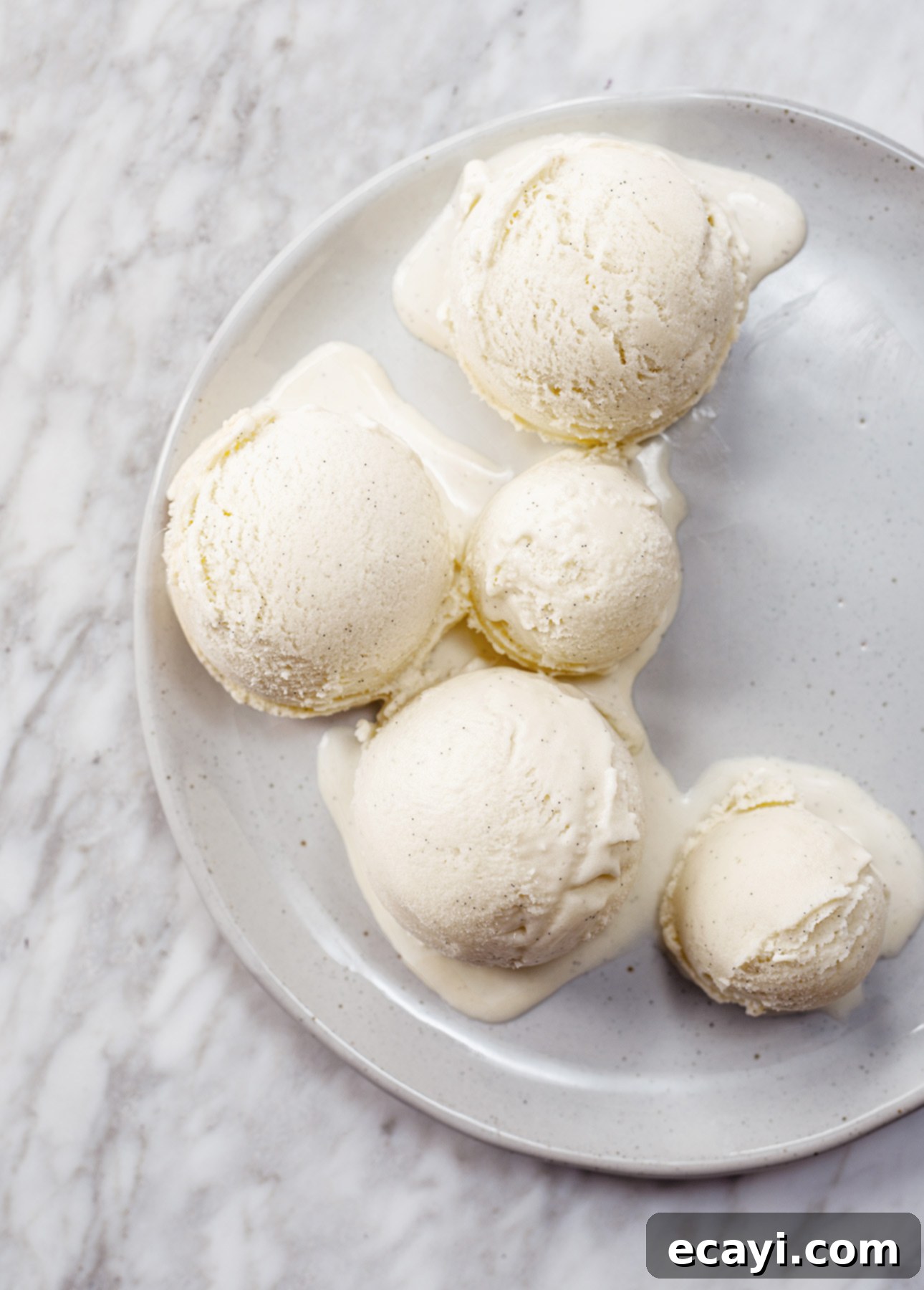 Crafting Creamy Vegan Gelato at Home 3 Five scoops of gelato are melting on a white plate set against a marble background. // FoodNouveau.com