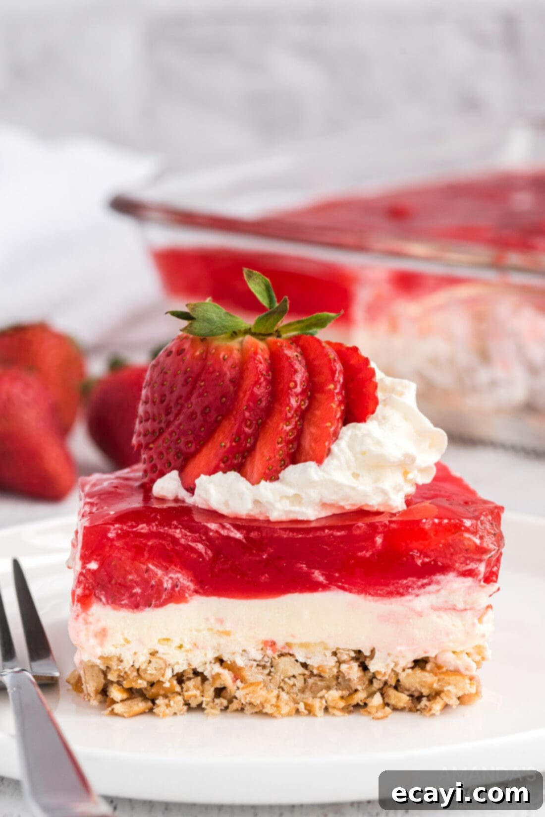 Strawberry Pretzel Delight 2 A perfectly sliced portion of strawberry jello pretzel salad showcasing its distinct layers: a golden pretzel crust, a white cream cheese layer, and a vibrant red strawberry jello topping.