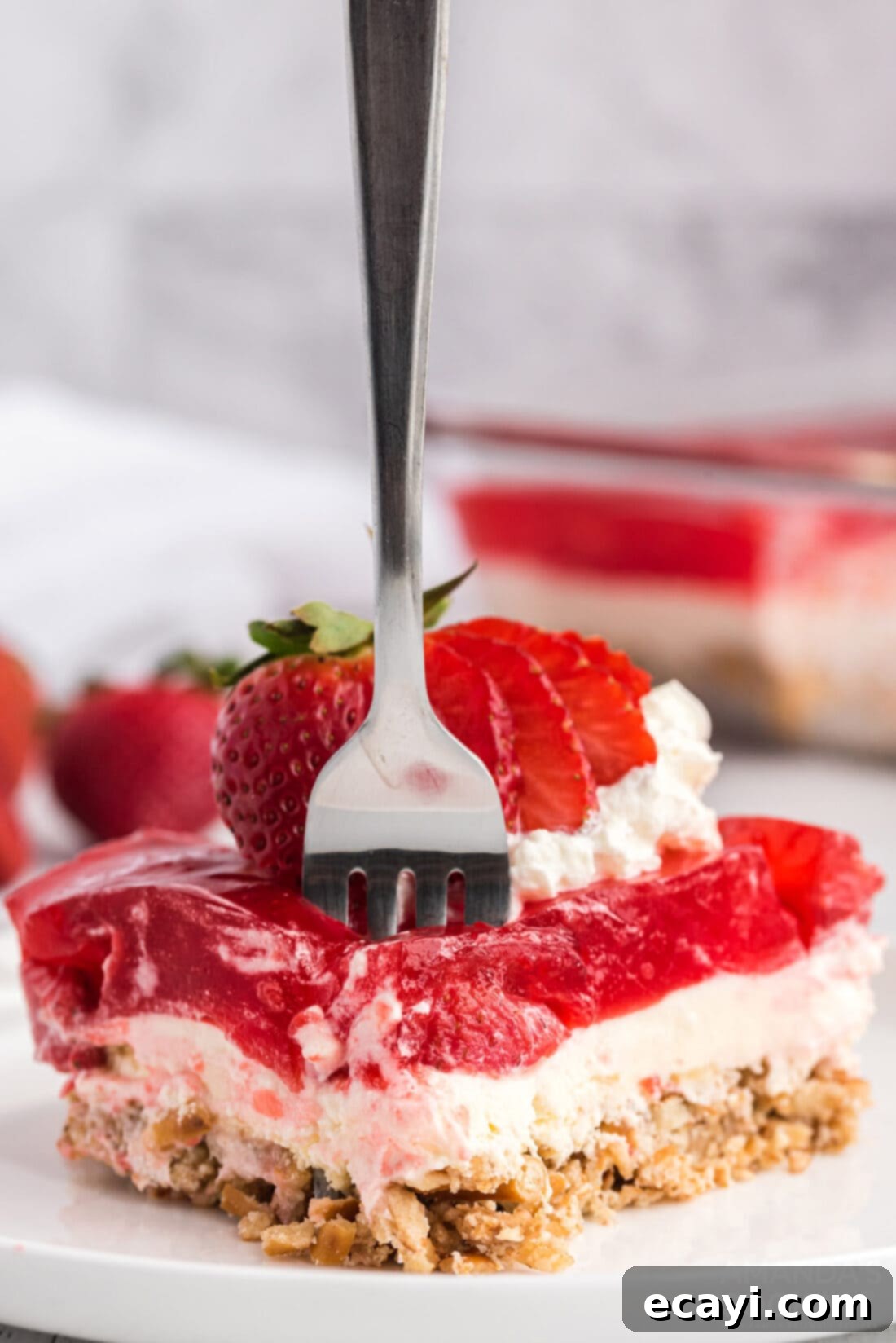 Strawberry Pretzel Delight 14 A fork taking a bite from a slice of Strawberry Pretzel Salad, highlighting the layers and texture.