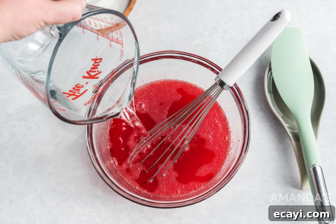 Strawberry Pretzel Delight 8 Adding cold water to the strawberry jello mixture, completing the liquid portion of the jello preparation.