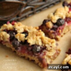 Berry Bliss Bars 5 A close up photo of two Berrylicious Cookie Bars, showing the texture of the cookie and the colorful berries.
