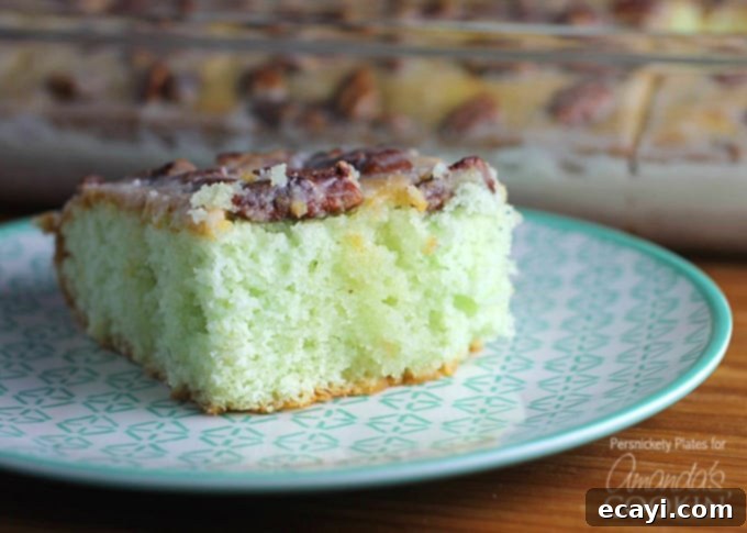 Learn how to make this super simple Pistachio Poke Cake that is always a crowd please. Pistachio Poke Cake is great as a take-along dessert for potlucks! A beautifully plated slice of Pistachio Poke Cake, highlighting the glazed top and tender crumb, ready to be enjoyed.