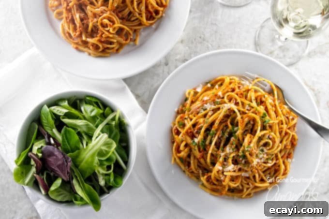 Sun-Kissed Tomato Pesto 4 An overhead photo of two plated of sun dried tomato pesto on pasta with a salad on the side.