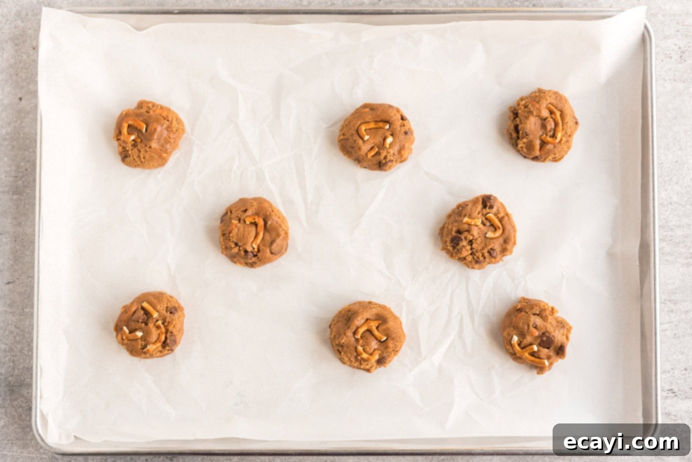 Twisted Pretzel Chocolate Chip Cookies 9 cookie dough balls with pretzels on a baking sheet