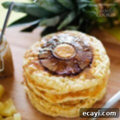 Tropical Pineapple Pancakes with Homemade Coconut Bliss 5 A close up photo of a stack of pineapple pancakes on a wooden cutting board.