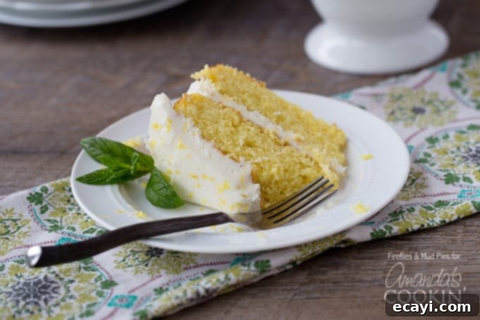Luscious Lemon Curd Poke Cake 5 A close up of a perfectly sliced lemon curd poke cake on a white plate, adorned with fresh mint leaves on the side, showing the moist yellow cake layers infused with lemon curd and frosted.