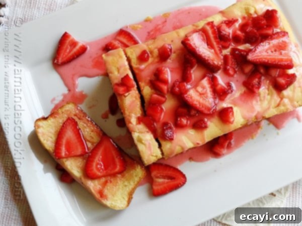 Luscious Lemon Curd Poke Cake 6 An overhead photo of a round Lemon Cream Cheese Pound Cake on a white platter, generously topped with an abundance of fresh, bright red strawberries, creating a visually appealing and delicious dessert ready for serving.