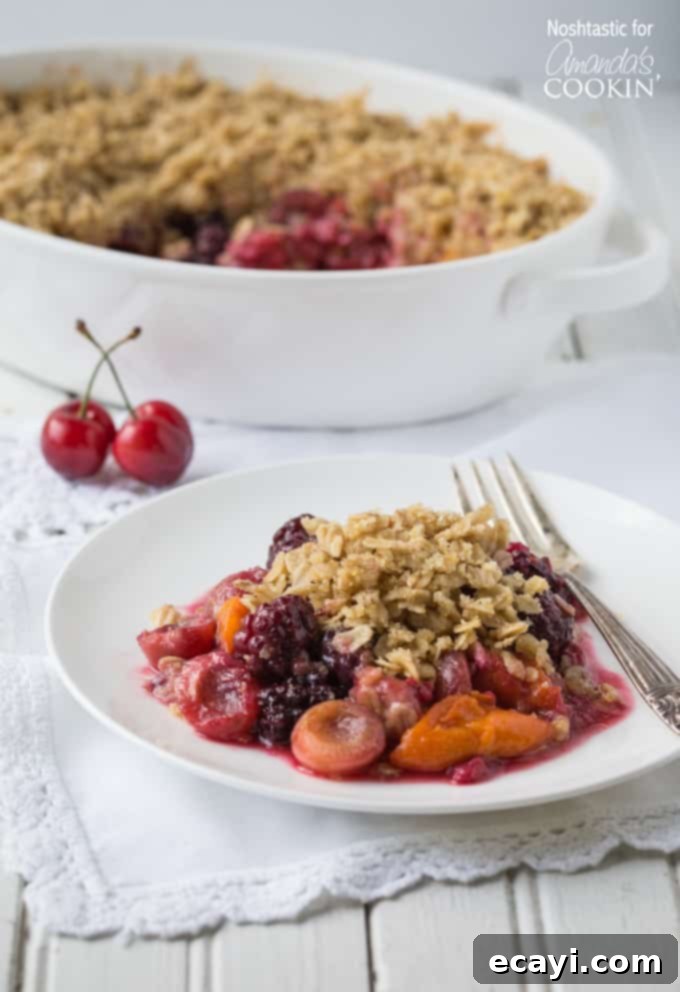 Golden Summer Fruit Crumble 3 Summer fruit crisp on a white plate with a fork on the side.