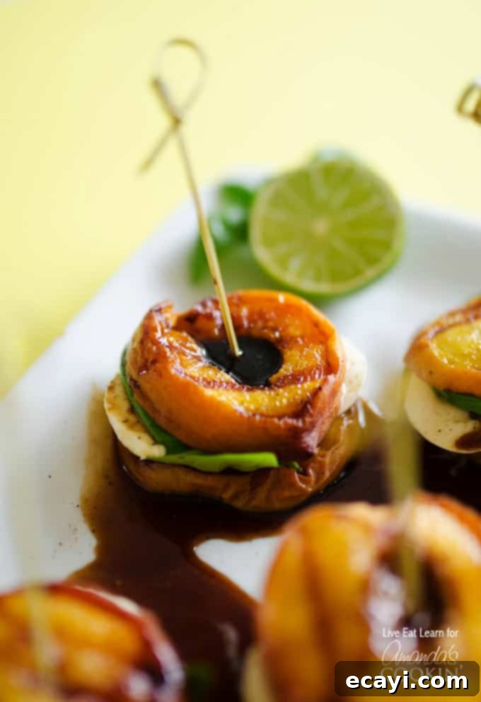 Smoky Peach Caprese 3 A close up of grilled peach caprese on a white platter with a lime wheel in the background.