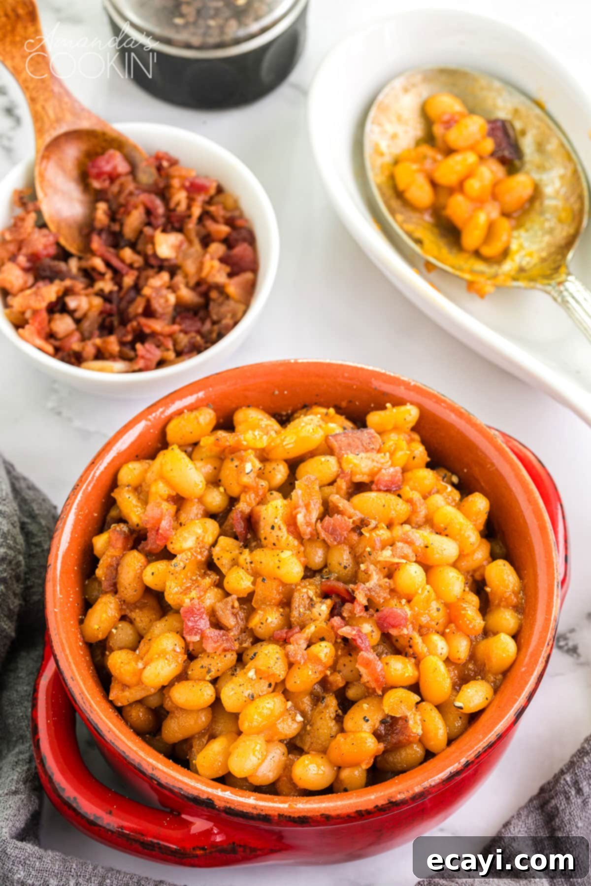 These homemade baked beans are baked in a delicious tangy sweet and savory sauce of brown sugar, maple syrup, ketchup, and apple cider vinegar. crock of homemade baked beans on a table