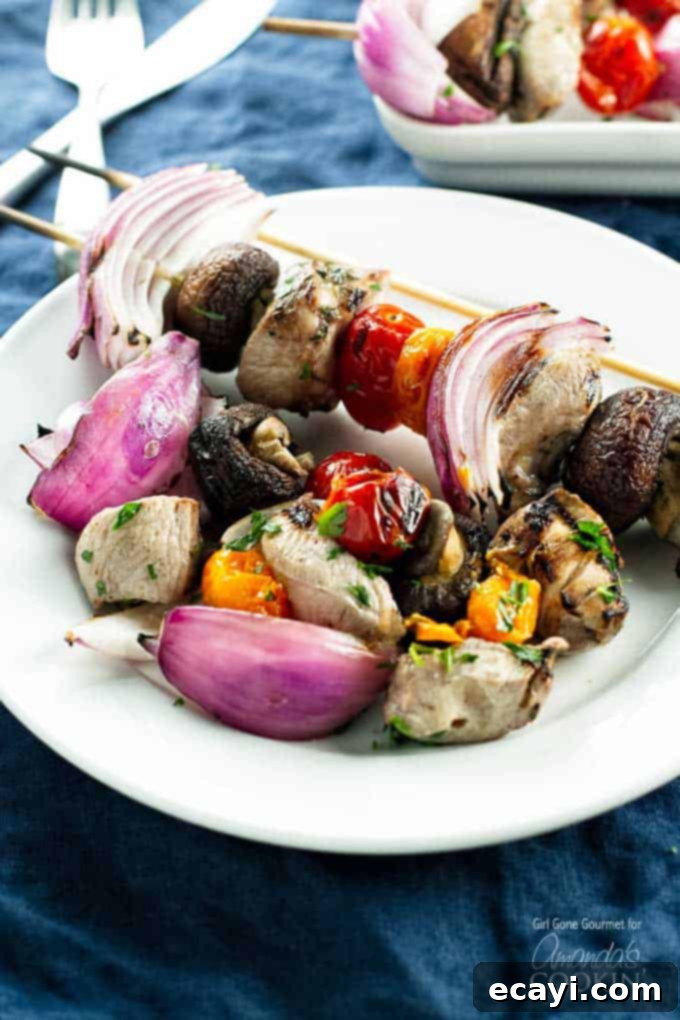 Tender Grilled Chicken Kebabs 2 A close up photo of marinated grilled chicken skewers on a white plate, showcasing perfectly charred chicken and colorful vegetables.