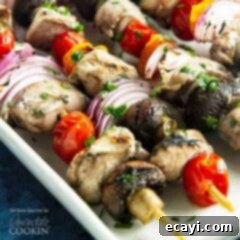 Tender Grilled Chicken Kebabs 7 A close up of marinated chicken skewers with tomatoes, red onions and mushrooms, showcasing a perfect grill.