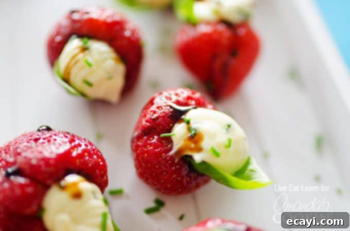 Brie Kissed Strawberries 4 A close up photo of strawberries stuffed with whipped brie and topped with a basil leaf.