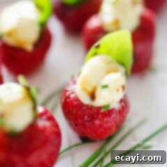 Brie Kissed Strawberries 5 A close up photo of strawberries filled with whipped brie and topped with a basil leaf.