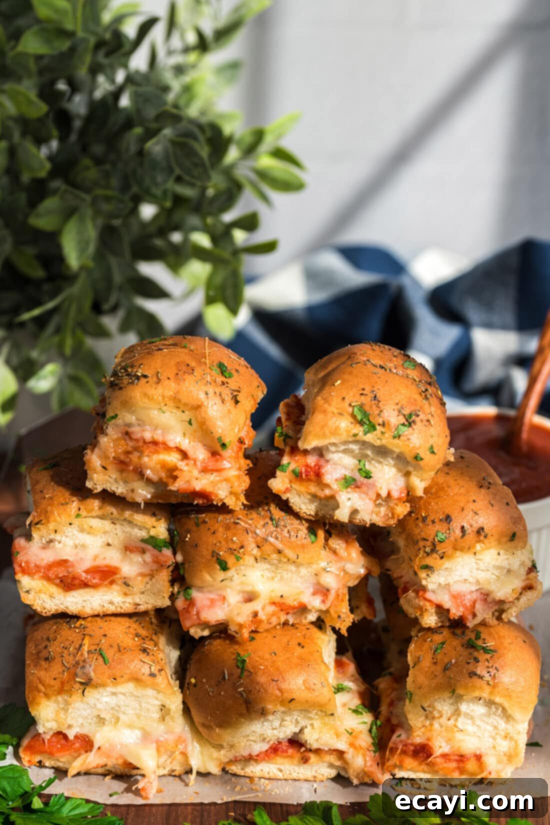 Cheesy Pizza Bites 2 A stack of golden brown pizza sliders, showing melted cheese and pepperoni inside