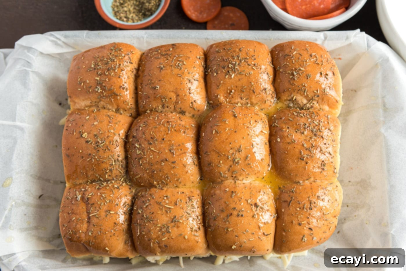 Cheesy Pizza Bites 11 Italian seasoning is sprinkled over the buttered tops of the pizza sliders, which are then covered with aluminum foil