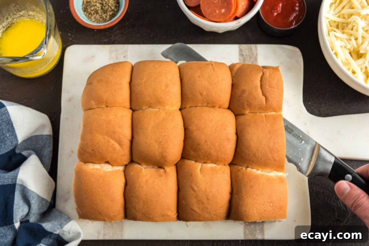 Cheesy Pizza Bites 5 A block of slider buns being sliced horizontally in half
