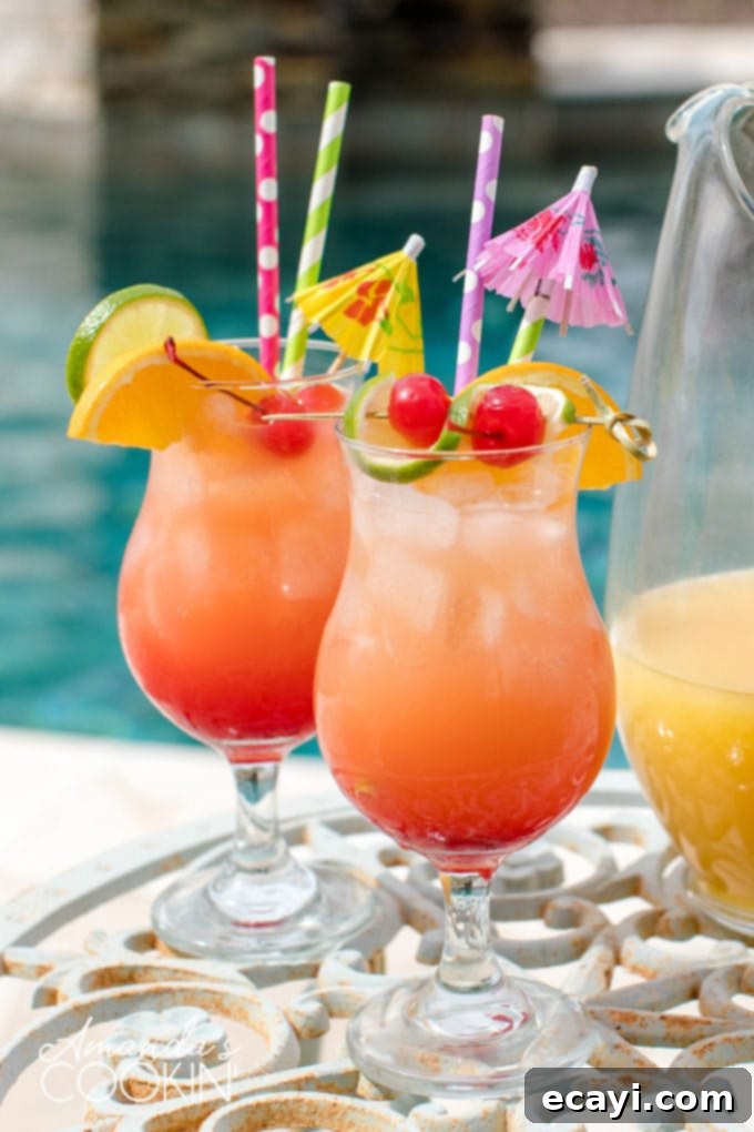 Punch of Paradise 2 Two glasses of vibrant rum punch served poolside, with a clear pitcher filled with the cocktail