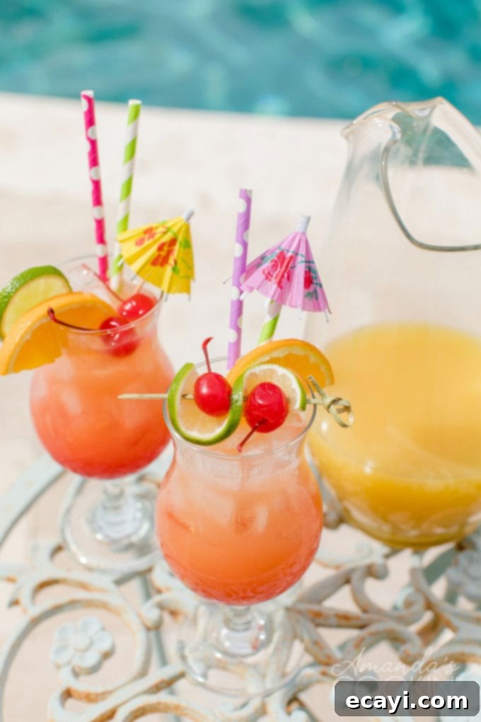 Punch of Paradise 3 Two glasses of vibrant rum punch served poolside, with a clear pitcher filled with the cocktail