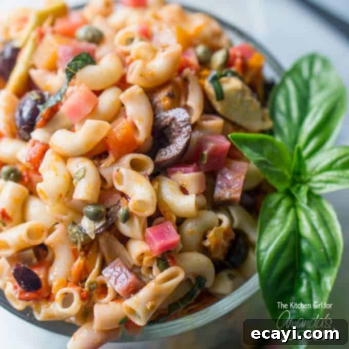 Sun-Drenched Mediterranean Pasta 3 A close up of a bowl filled with Mediterranean pasta salad and a basil leaf on the side.