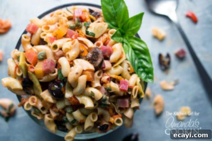 Sun-Drenched Mediterranean Pasta 4 A close up of a bowl filled with Mediterranean pasta salad and a basil leaf on the side.