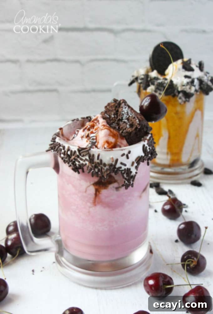 Freakshakes Wildly Indulgent Shakes 2 A photo of a vibrant cherry fudge chunk freakshake in the foreground with a double caramel cookie crunch freakshake subtly blurred in the background. Each is generously topped and garnished.