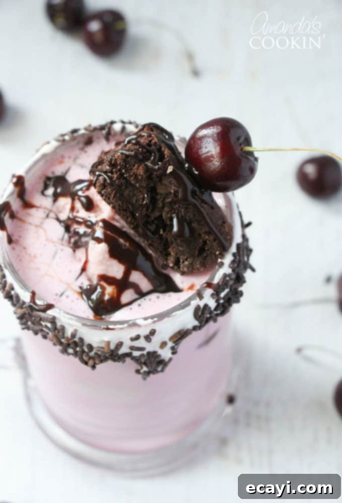 Freakshakes Wildly Indulgent Shakes 8 A captivating close-up overhead shot of a Cherry Fudge Chunk Freakshake, impeccably assembled and ready to be served, showcasing its layers and delicious toppings.