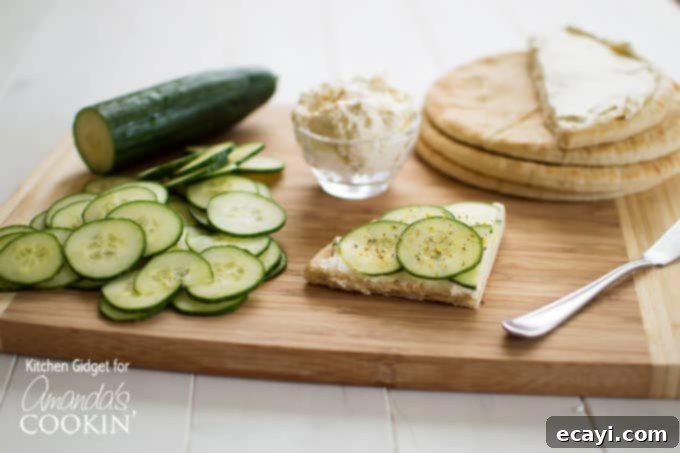 What do you get when you combine crisp cucumbers, zesty cream cheese, and soft pita bread? These mouthwatering cucumber sandwiches! cucumbers, pita, and spread with cucumber sandwich on a wooden cutting board