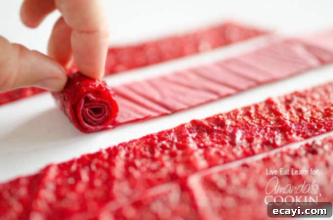 Simple DIY Fruit Leather 4 A close up of homemade fruit roll ups being rolled up with parchment paper.