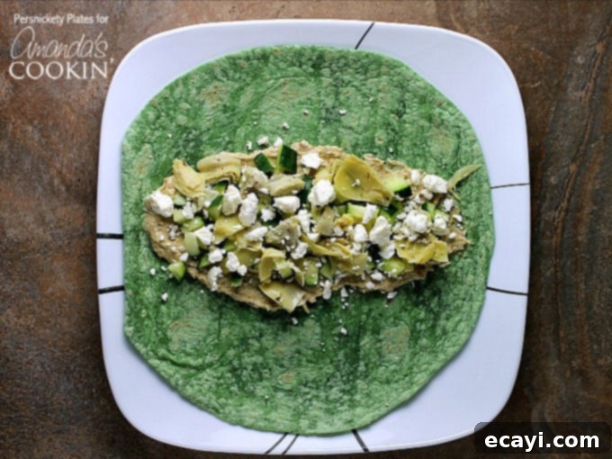 Sun-Drenched Mediterranean Wrap 3 An overhead photo of chopped artichoke hearts, diced cucumber, hummus and crumbled feta on a spinach wrap.