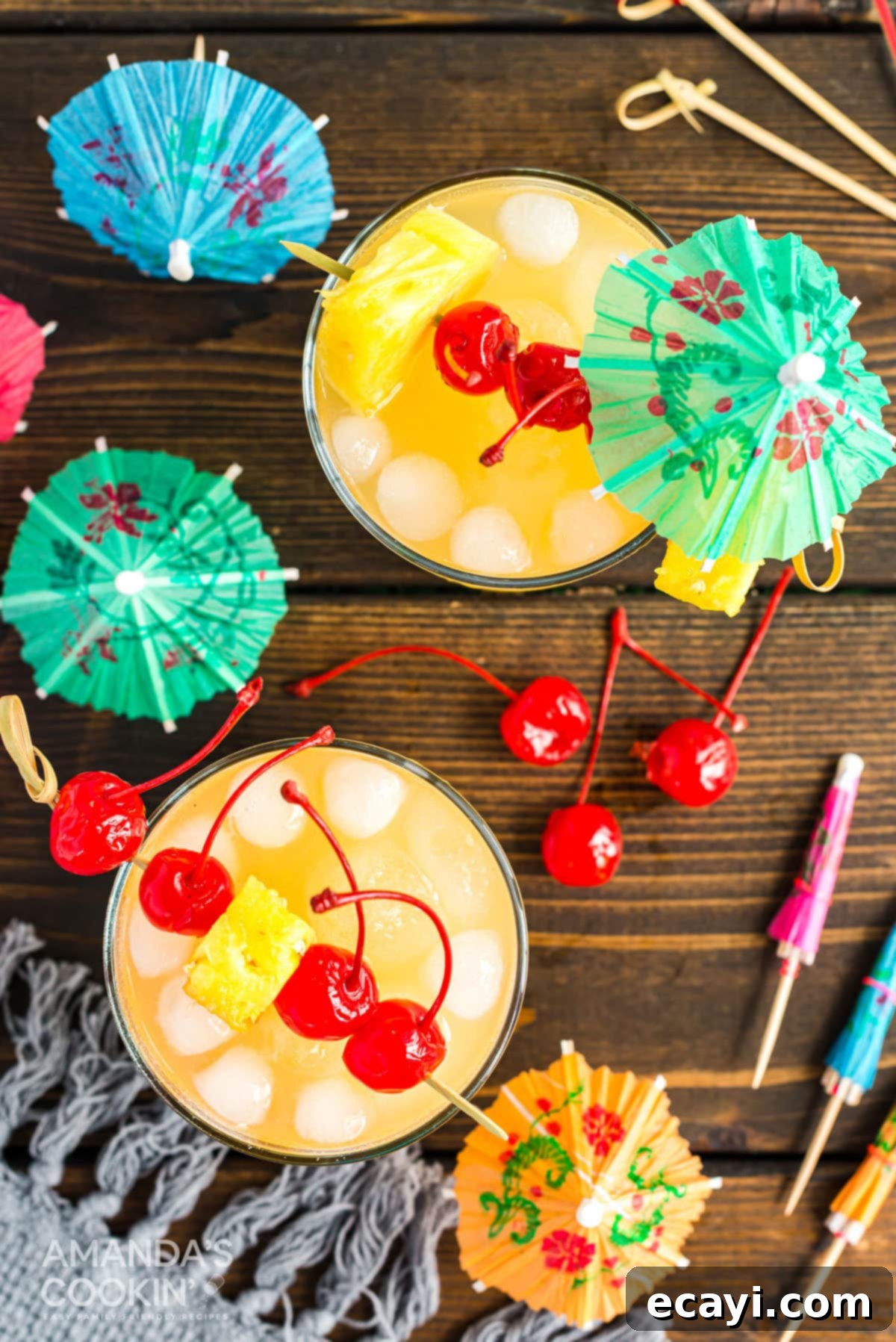 A basic Mai Tai is easy to make. This rum cocktail has combines almond, lime, and tropical fruit flavors. Great for summer and reminds you of the beach! An overhead shot showcasing two beautifully garnished Mai Tai cocktails, complete with maraschino cherry and pineapple wedges, set for a tropical celebration.