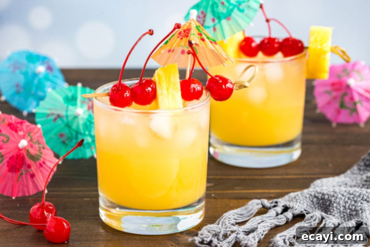A basic Mai Tai is easy to make. This rum cocktail has combines almond, lime, and tropical fruit flavors. Great for summer and reminds you of the beach! A captivating close-up of a Mai Tai cocktail, artfully garnished with a cherry and pineapple, inviting you to take a refreshing sip.