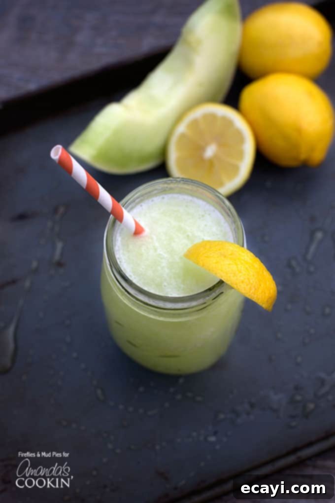 Zesty Honeydew Chill 2 A beautiful overhead shot of a mason jar filled with a light green honeydew lemon slush, garnished with a fresh lemon wedge and served with a charming red and white striped straw. The perfect summer drink.